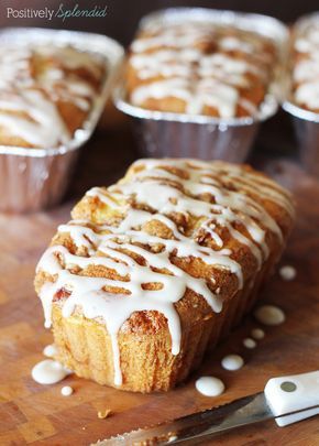 there is a loaf of bread with icing on the table next to some muffins