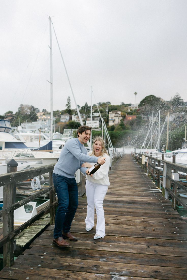 a man and woman standing on a dock next to boats