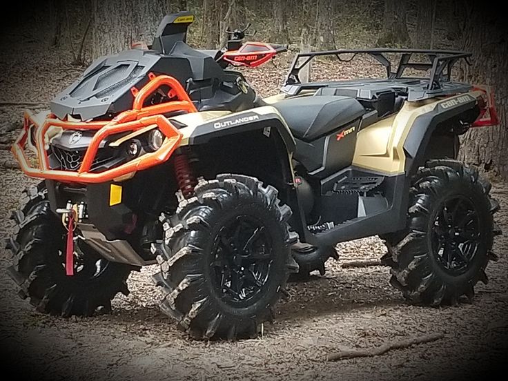 an orange and black four - wheeler parked in the dirt with mud tires on it