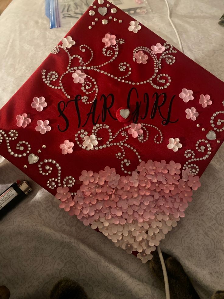 a red graduation cap with pink and white flowers on it that says star girl in black lettering