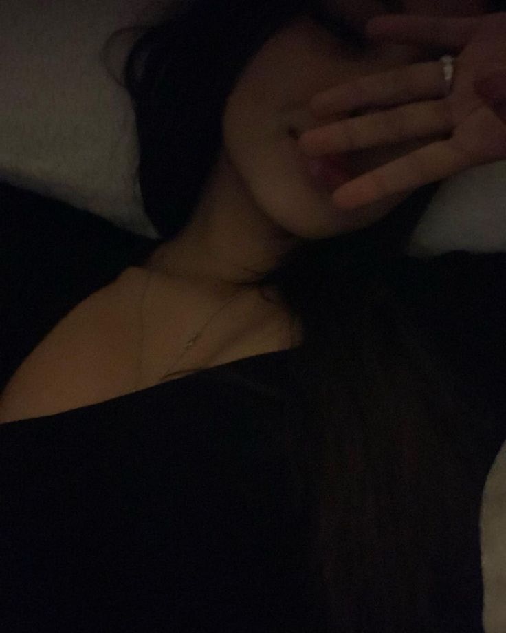 a woman laying in bed with her hand on her face