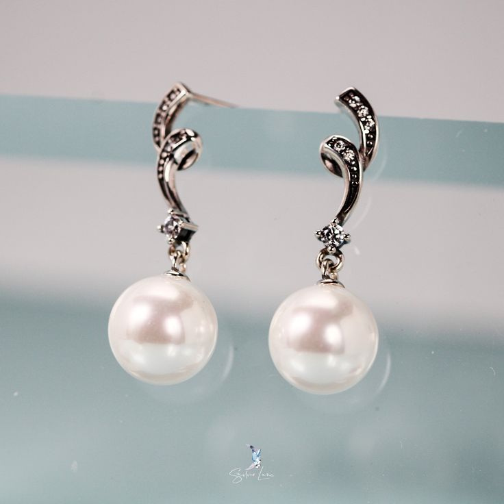 Enhance your style with these stunning sterling silver pearl dangle drop earrings! The elegant design features glistening cubic zirconia for a touch of sparkle. Perfect for any occasion, these earrings will elevate your look and make you feel confident and glamorous! Sold as a pairMaterials: 925 sterling silver, shell pearlsFinish: platinum plate, oxidationDimensions: 1.06 x 0.25 in Jewelry Care: See more information about how to care for your jewelry here. Shipping Policy: Orders will be shippe Exquisite Sterling Silver Pearl Earrings For Evening, Formal Sterling Silver Diamond Earrings With Pearl Drop, Exquisite Silver Dangle Pearl Earrings, Elegant Sterling Silver Pearl Earrings For Evening, Evening Pearl Earrings In Diamond White, Elegant Diamond Crystal Earrings, Diamond White Pearl Earrings For Evening, Elegant Pearl Pendant Earrings For Party, Elegant Silver Pearl Earrings For Evening