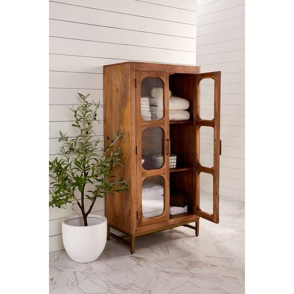 a wooden cabinet sitting next to a potted plant on top of a white floor