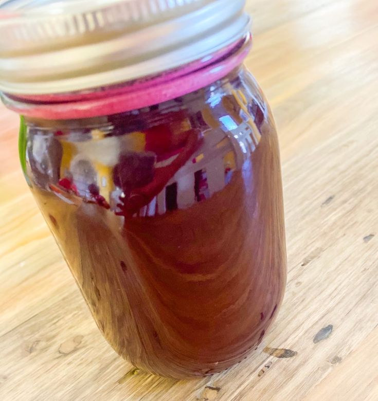 a jar filled with liquid sitting on top of a wooden table