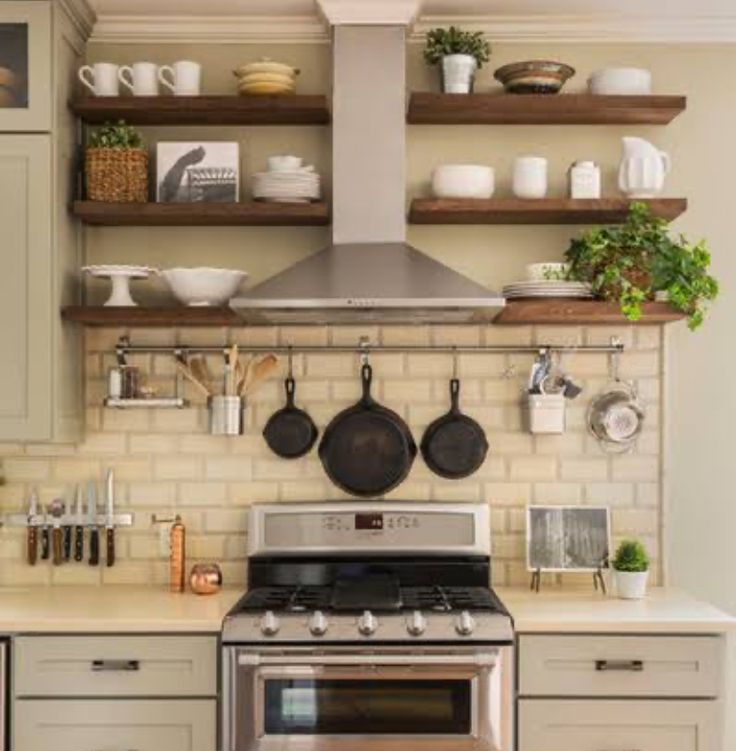 a stove top oven sitting inside of a kitchen next to wooden shelves filled with pots and pans