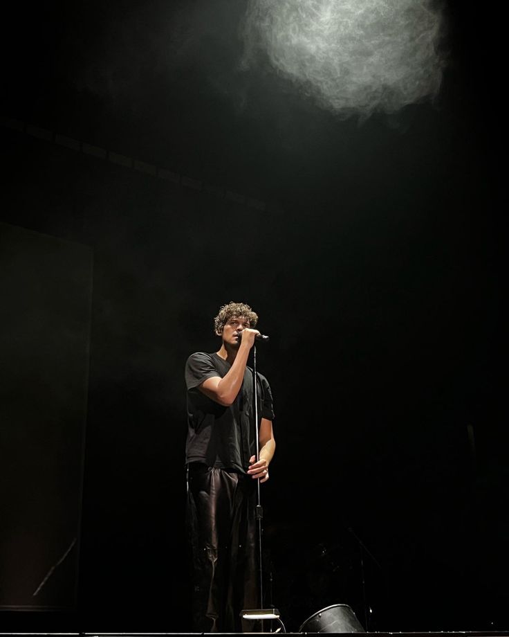 a man standing on top of a stage holding a microphone in front of his face