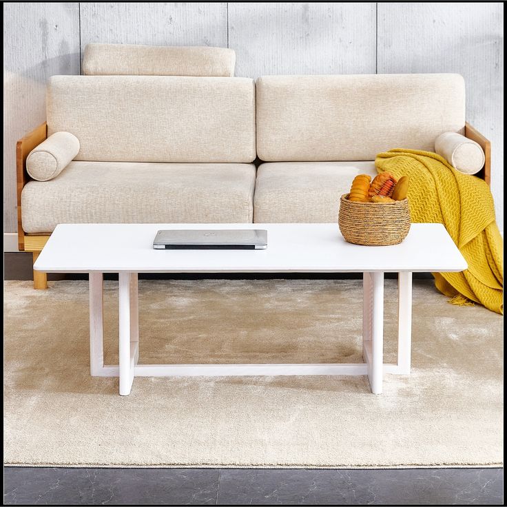 a white coffee table sitting on top of a carpeted floor next to a couch