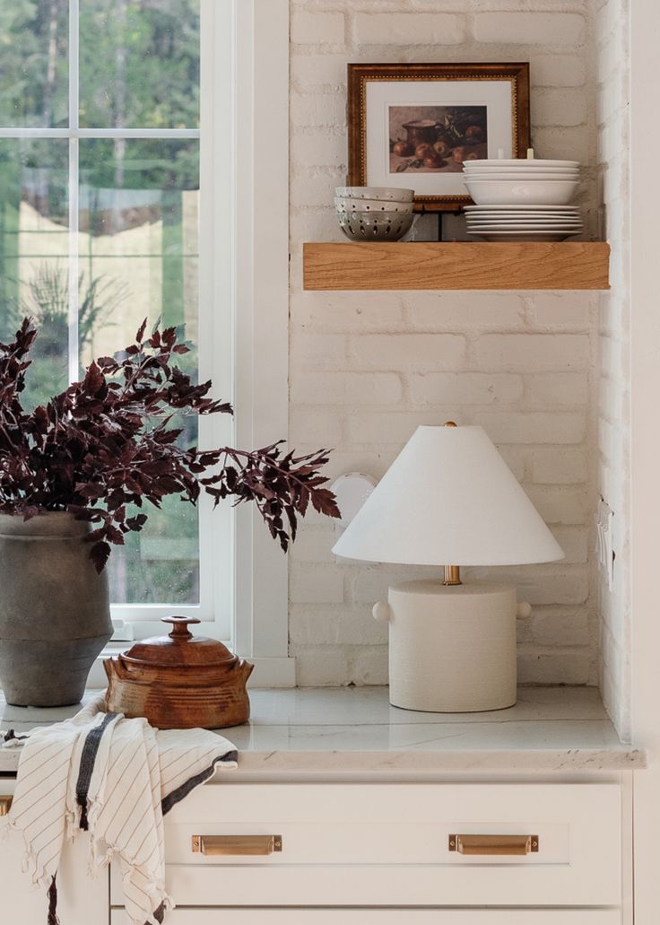 a white kitchen counter topped with a lamp and potted plant