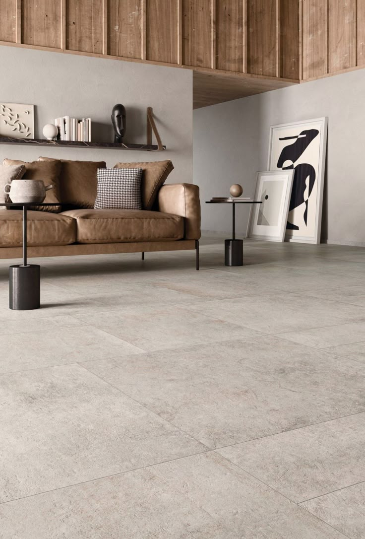 a living room with grey tile floors and wooden furniture on the floor, along with a brown leather couch