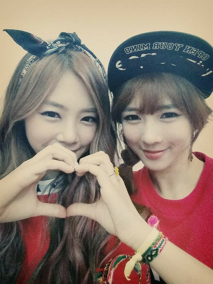 two young women posing for a photo with their hands in the shape of a heart