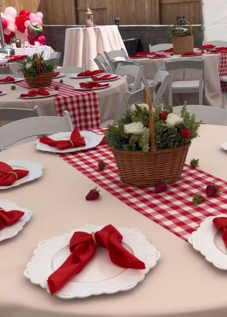 the table is set with red and white plates, napkins, and strawberries