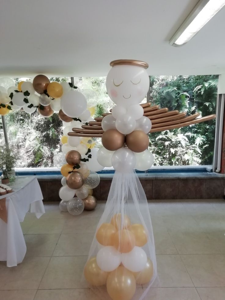 an angel balloon in a bag with gold and white balloons hanging from it's sides