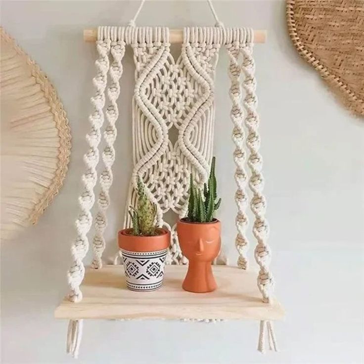 a macrame wall hanging with two potted cacti and one cactus