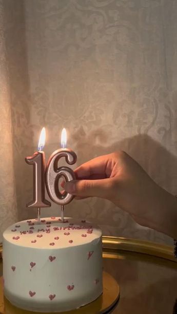 a person holding a birthday cake with candles in the shape of the number sixteen on it