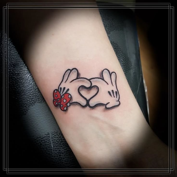 a couple of rabbits with hearts in their ears tattoo on the left inner arm and wrist