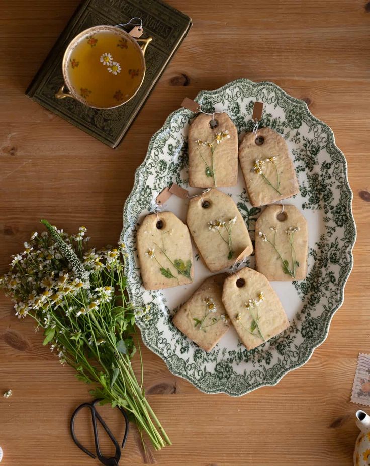 some cookies are sitting on a plate next to flowers and a teapot with a cup