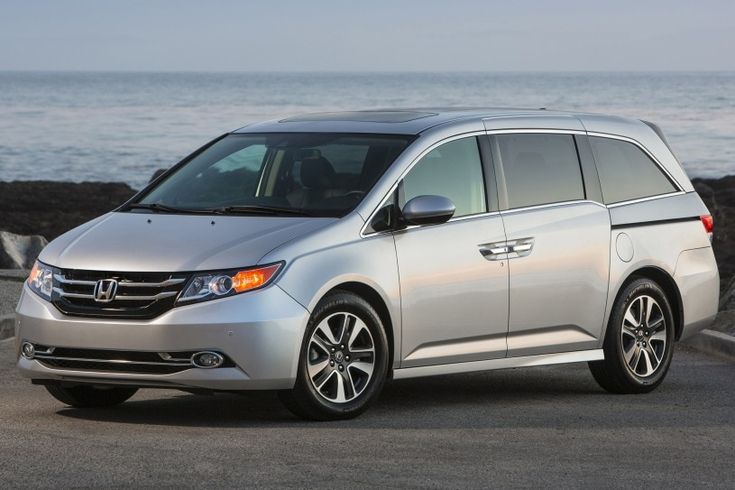 a silver van is parked on the side of the road near the water and rocks