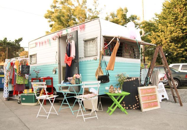 an old camper is parked on the side of the road with chairs and tables