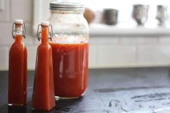 two bottles filled with sauce sitting on top of a counter