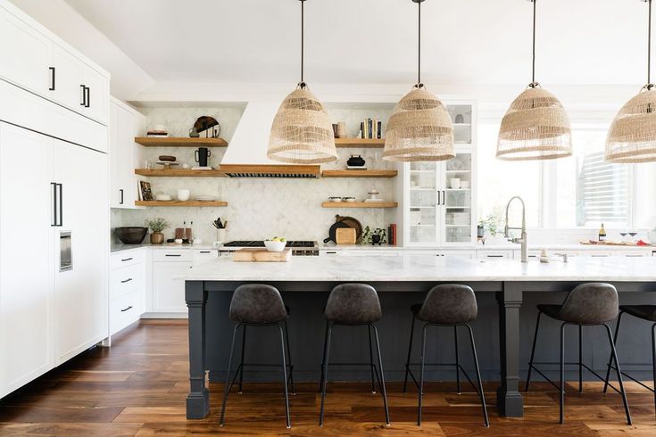 a kitchen with wooden floors and hanging lights above the countertop, along with bar stools