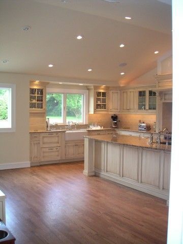 a large kitchen with wooden floors and white cabinets