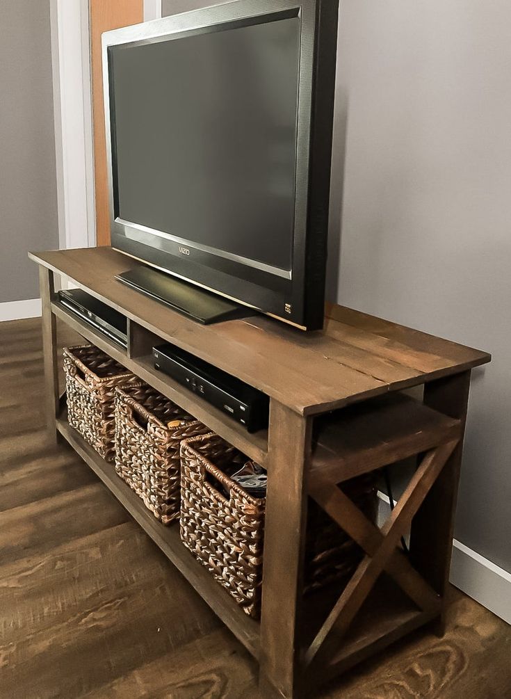 a flat screen tv sitting on top of a wooden entertainment center with baskets underneath it