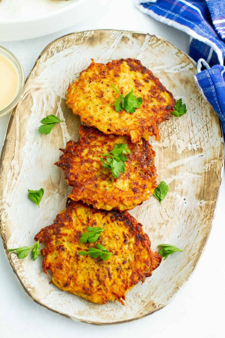 three crab cakes on a plate with sauce and napkins next to it, ready to be eaten