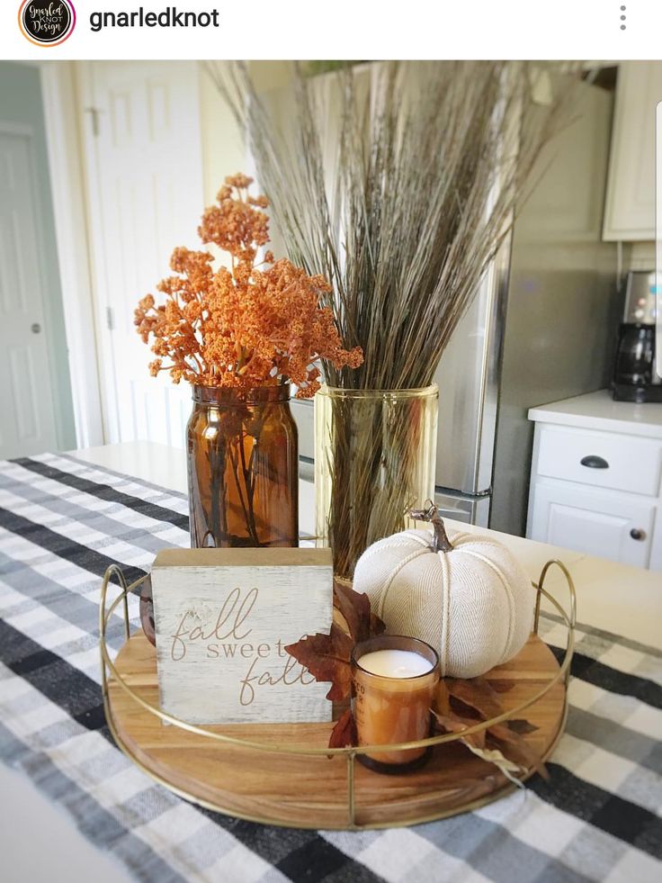 there is a plate with some pumpkins on it and two vases filled with flowers