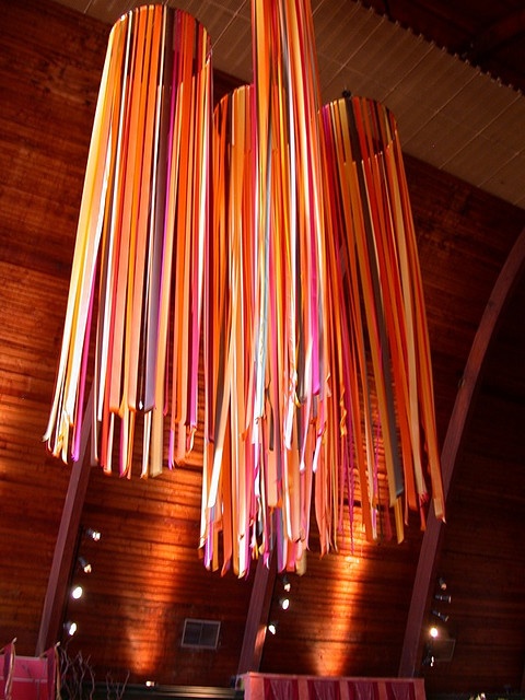 colorful lights hanging from the ceiling in a room with wood paneling and wooden walls