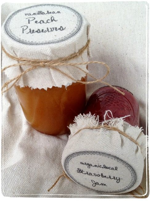 two jars of jam sitting next to each other on a white cloth covered tablecloth