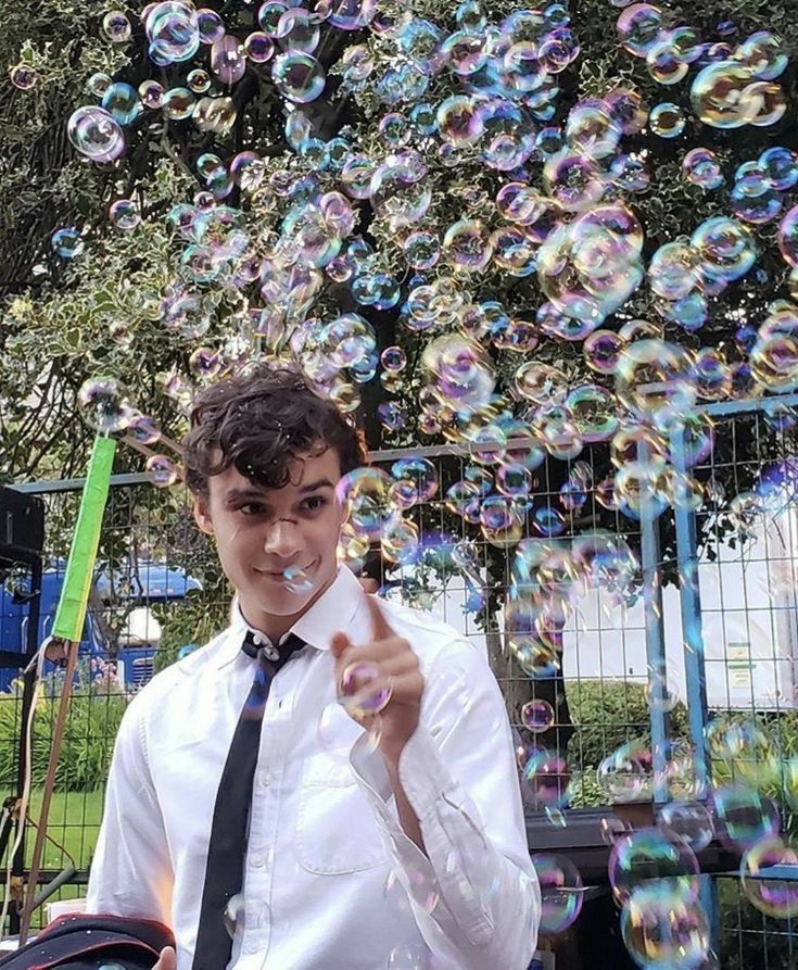 a young man is standing in front of a bunch of soap bubbles