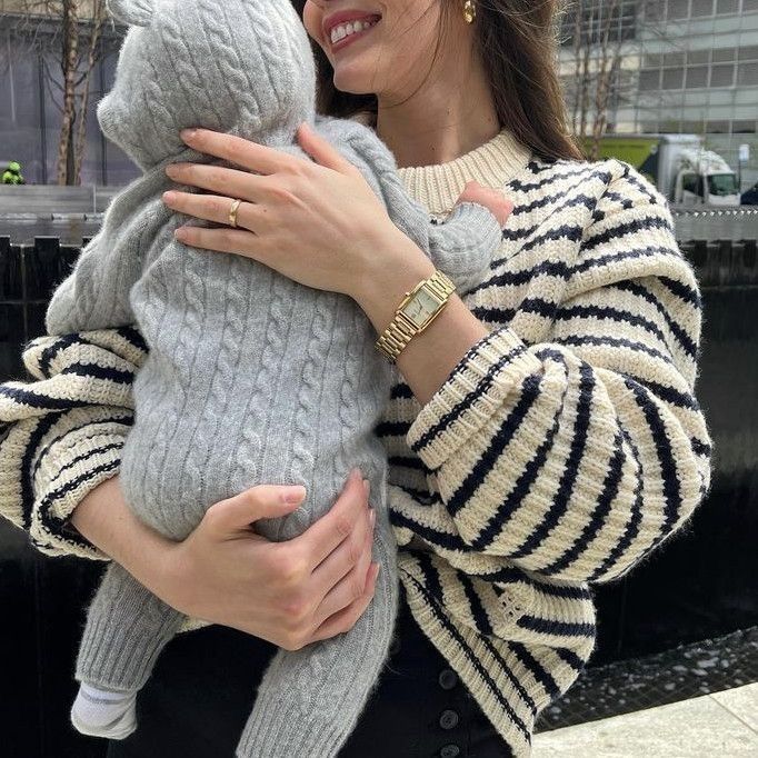 a woman is holding a baby in her arms and wearing a knitted bear sweater