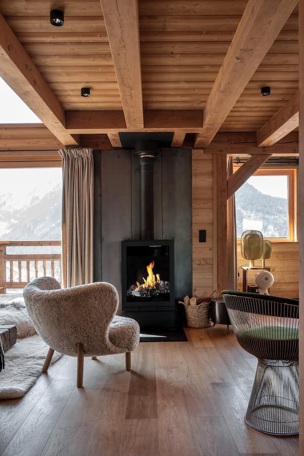 a living room filled with furniture and a fire place in the middle of a wooden floor