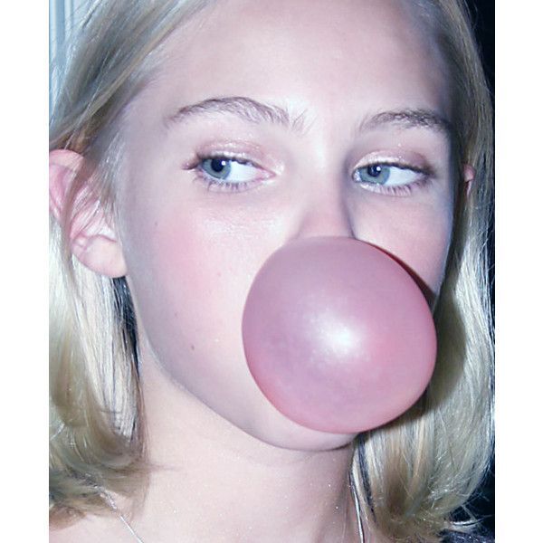 a woman with blonde hair blowing a bubble on her nose