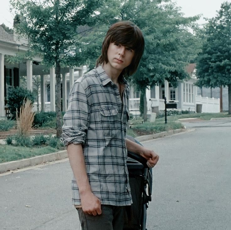 a young man is standing on the street with his skateboard in hand and looking at the camera