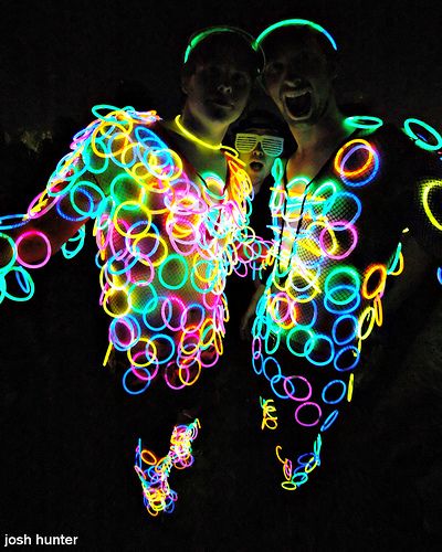 two people standing next to each other with neon rings around them and the words mean as many glow sticks as possible