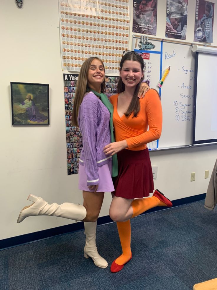 two girls are posing in front of a whiteboard