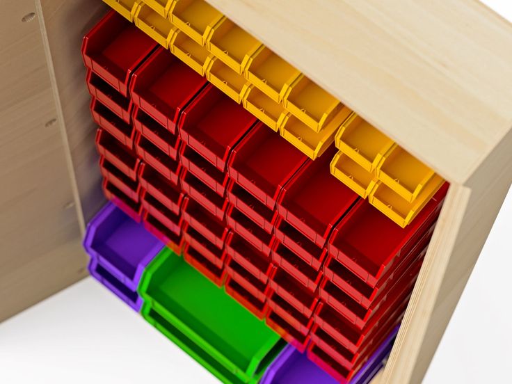 colorful bins are stacked on top of each other in a wooden cabinet with white background