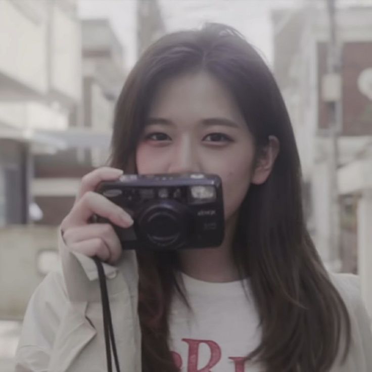 a woman taking a selfie with a camera in front of her face on the street