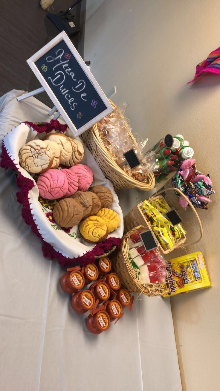 a table topped with lots of different types of cookies and pastries next to a chalkboard sign