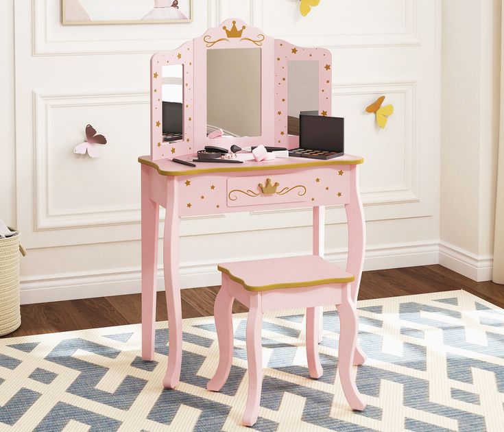 a pink vanity table with mirror and stool