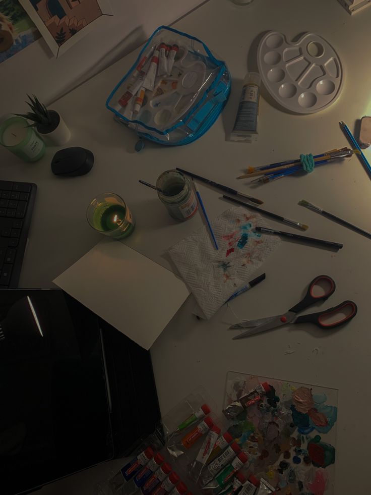 there are many crafting supplies on the table next to a laptop and other items