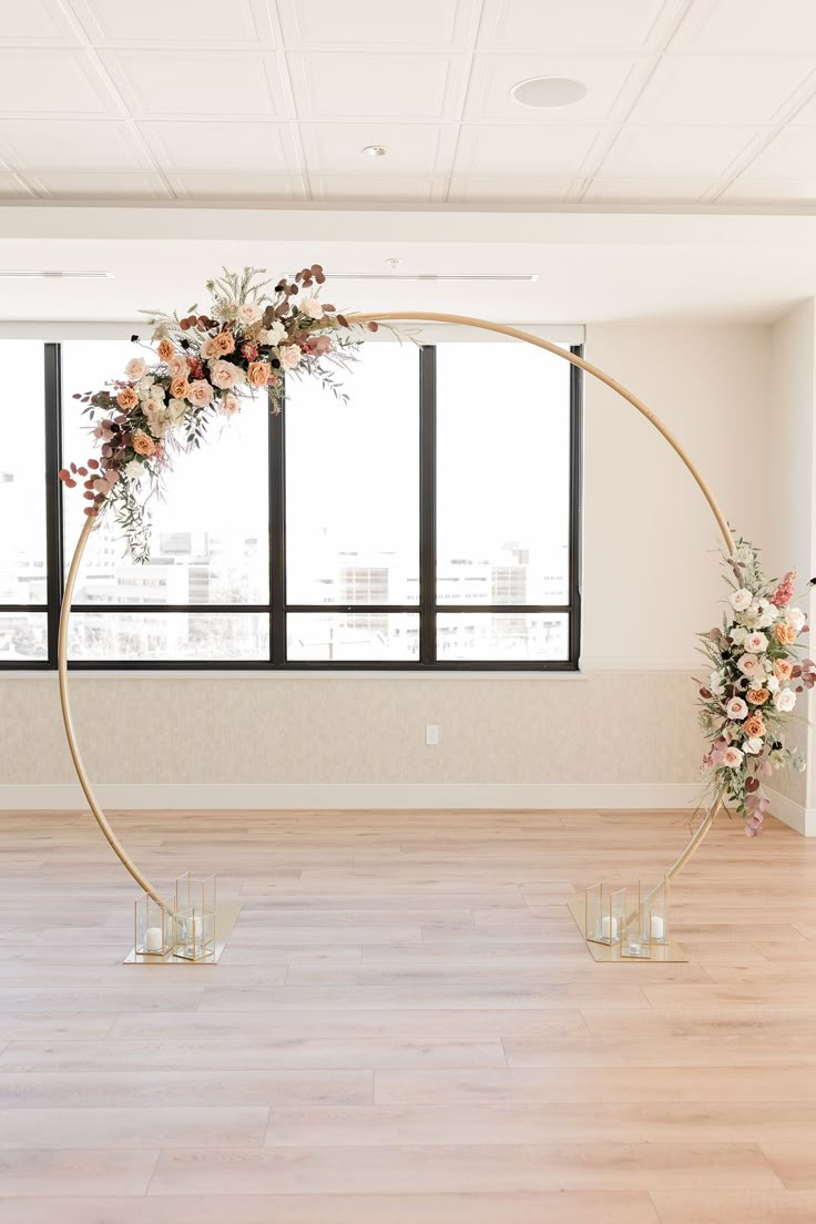 an empty room with flowers and candles on the floor in front of large windows,