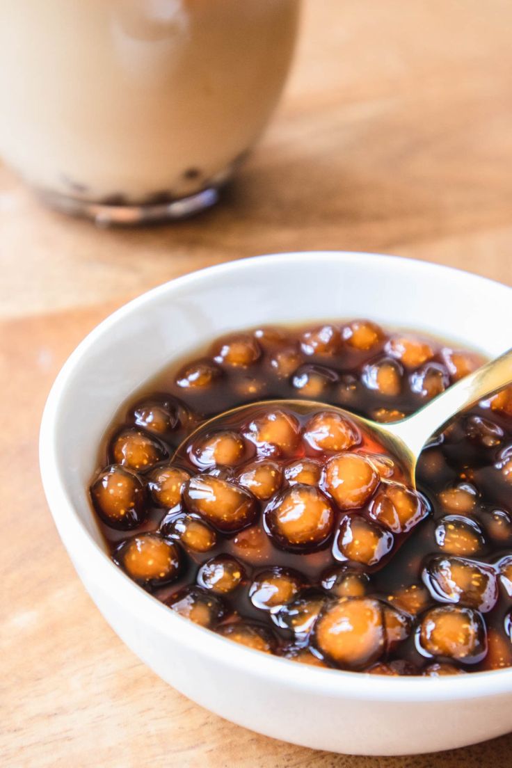 a white bowl filled with food next to a brown cup on top of a wooden table