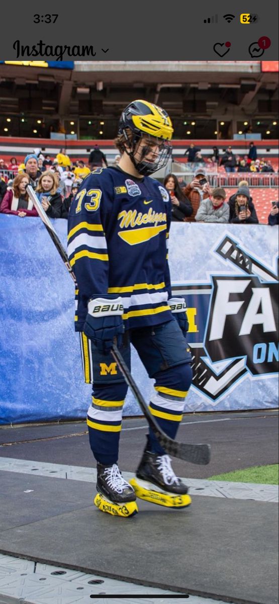 a hockey player is standing on the ice with his stick in hand and fans are watching