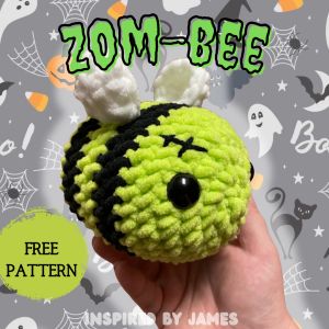 a hand holding a small crocheted toy with the words zoom bee on it