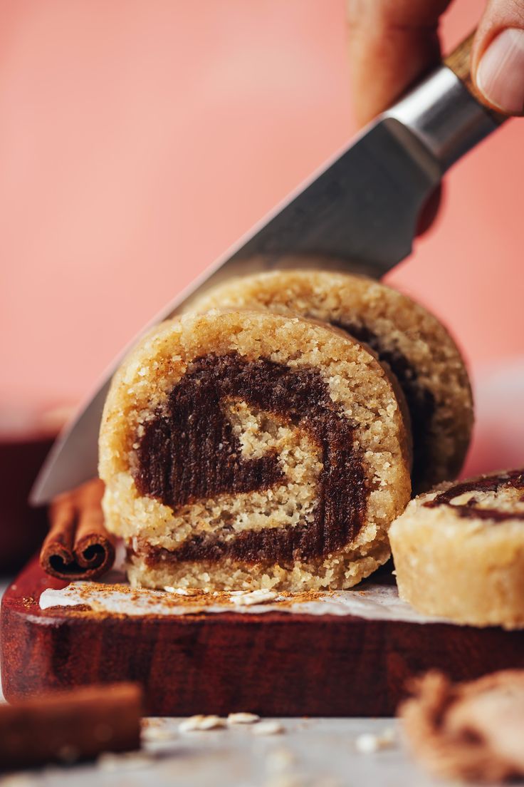 someone is cutting into a cinnamon roll with a knife