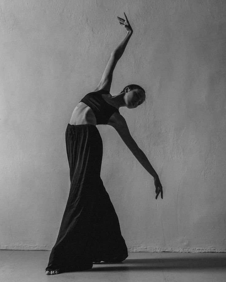 a black and white photo of a woman in a long dress doing a dance pose