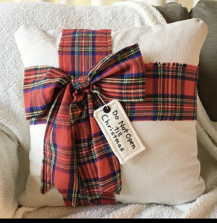 a plaid pillow with a ribbon tied around it and a tag attached to the pillow