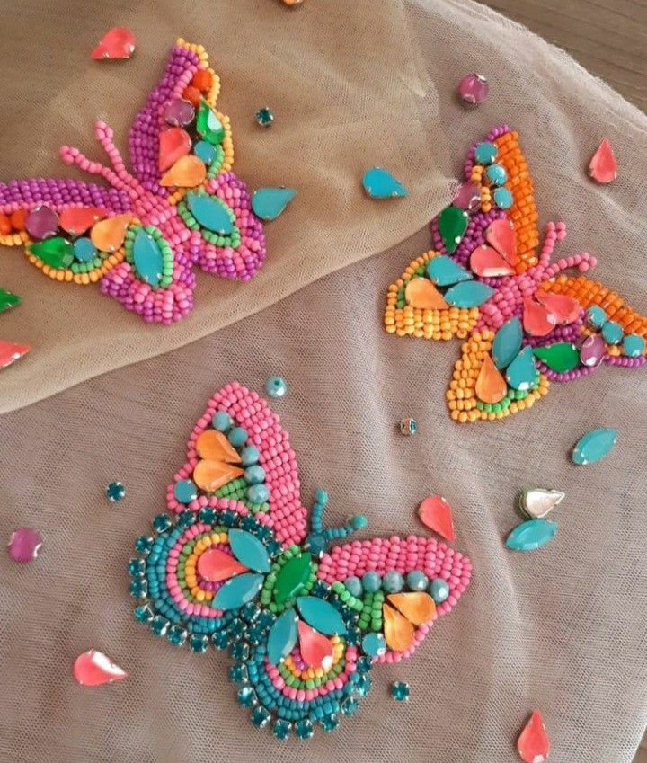 two colorful beaded butterflies sitting on top of a table